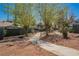 A view of a neighborhood walkway with desert landscaping and mature trees at 4032 Great Plains Way, Las Vegas, NV 89121