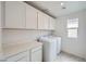 Bright laundry room with modern washer and dryer, built-in cabinets, and a convenient countertop at 4727 Agave Cactus St, North Las Vegas, NV 89031