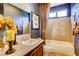 Well-lit bathroom with decorative tile, framed art and floral accents, tub, and vanity at 7210 El Malpais St, Las Vegas, NV 89118