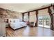 Light-filled primary bedroom with hardwood floors, brick accent wall, and outdoor access at 7210 El Malpais St, Las Vegas, NV 89118