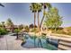 Stunning pool with rock features, spa, and lush landscaping for a tropical backyard retreat at 7210 El Malpais St, Las Vegas, NV 89118
