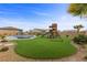 A playful backyard oasis featuring a pool with slide, spa, and fun playset on manicured artificial turf at 7277 W Landberg Ave, Las Vegas, NV 89178