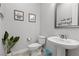 Charming half bathroom offering a pedestal sink, toilet, decorative mirror, and unique wall decor at 7277 W Landberg Ave, Las Vegas, NV 89178