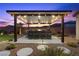 Outdoor kitchen with bar seating, grill, and overhead lighting, perfect for backyard entertainment at 7277 W Landberg Ave, Las Vegas, NV 89178