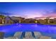 Backyard pool with slide, sun loungers and palm trees, illuminated against a vibrant dusk sky at 7277 W Landberg Ave, Las Vegas, NV 89178