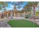 Landscaped backyard with a putting green, gravel, covered patio, and mature trees, creating a relaxing outdoor space at 7368 Mission Hills Dr, Las Vegas, NV 89113