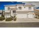 A beautiful two-story white house featuring a three-car garage, tile roof, and well-maintained landscaping at 7464 Forestdale Ct, Las Vegas, NV 89120