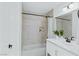 Bright bathroom featuring marble tiled walls, shower-tub, and sleek white vanity at 7904 Fossil Creek Ln # 101, Las Vegas, NV 89145