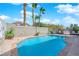 Backyard pool with palm trees, desert landscaping, privacy wall, and outdoor seating at 8468 W Gilmore Ave, Las Vegas, NV 89129