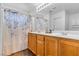 Bathroom with double vanity, wood cabinets, large mirror, and shower with decorative curtain at 8932 Jaquita Ave, Las Vegas, NV 89149