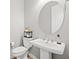 Half bathroom featuring a pedestal sink, round mirror, and modern toilet at 10186 Zeta Tucana St, Las Vegas, NV 89143