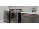 Laundry room with front-loading washer and dryer, white countertops, and dark wood cabinets at 10186 Zeta Tucana St, Las Vegas, NV 89143