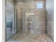 Luxurious walk-in shower with gray tiling and decorative pebble flooring at 10186 Zeta Tucana St, Las Vegas, NV 89143