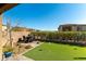 Backyard featuring artificial grass, mature hedges, and a patio with dining furniture at 12381 Liberty Beacon Ave, Las Vegas, NV 89138