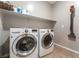 Well-lit laundry room featuring a modern washer and dryer set with storage shelves above at 12381 Liberty Beacon Ave, Las Vegas, NV 89138