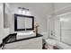 Well-lit bathroom featuring a modern sink, dark countertop and framed mirror, plus a glass-enclosed shower and commode at 1311 Watercreek Dr, North Las Vegas, NV 89032