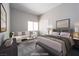 This staged bedroom features a comfortable sitting area, a neutral color palette, and bright window at 2528 Furnace Creek Ave, Henderson, NV 89074