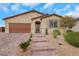 Single-story home with a brick driveway, desert landscaping, and a neutral colored facade and a two car garage at 3018 Carothers Ct, North Las Vegas, NV 89032