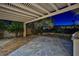 Backyard featuring a covered patio, spacious stone pavers, a built-in grill, and manicured landscaping at twilight at 3163 Elk Clover St, Las Vegas, NV 89135