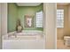 Bathroom features a deep soaking tub with tile surround, green accent wall, and glass block window at 3163 Elk Clover St, Las Vegas, NV 89135