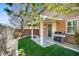 A covered patio features a built-in grill, opening to green grass, and a sliding glass door for easy indoor/outdoor living at 4036 W Bird Man Ln, North Las Vegas, NV 89084