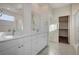 Bright bathroom with double sinks, white cabinets, and a walk-in shower, complemented by a view into the large closet at 513 Founders Creek Ave, North Las Vegas, NV 89084