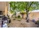 Private backyard with gravel landscaping, mature trees, and patio area with grill at 7172 Painted Paradise St, Las Vegas, NV 89131
