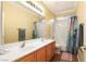 This bathroom features a double sink vanity with wood cabinets, a large mirror, a shower and tub combo, and tile floors at 7172 Painted Paradise St, Las Vegas, NV 89131