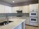 Bright kitchen features white cabinets, mosaic backsplash, stainless steel appliances, and quartz countertops at 8122 Delphi Ct, Las Vegas, NV 89117