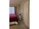Bedroom features a large window, bright carpet, red bedding, and closet space for a comfortable and organized space at 824 Holly Lake Way, Henderson, NV 89002