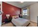 Comfortable bedroom with unique red accent wall, modern lighting, and a large window at 9380 Lunar Effect St, Las Vegas, NV 89143