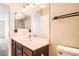 Bathroom with dark wooden vanity, decorative mirror, and toilet at 10115 Tree Bark St, Las Vegas, NV 89183