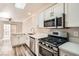 Updated kitchen features stainless steel appliances, white cabinets, and gray wood floors at 10115 Tree Bark St, Las Vegas, NV 89183