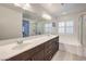 Bright bathroom featuring a dual sink vanity, large mirror, separate shower and tub, and plantation shutters at 10490 Palmadora St, Las Vegas, NV 89178
