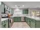 Well-designed kitchen boasts sage green cabinetry, stainless steel appliances, quartz countertops, and tile backsplash at 11157 Mezzana St, Las Vegas, NV 89141