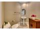 Stylish powder room with pedestal sink, oval mirror, decorative cabinet, and marble flooring at 2 Cerchio Centrale, Henderson, NV 89011
