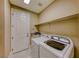 Well-equipped laundry room with modern washer and dryer, storage shelving, and granite countertop at 2 Cerchio Centrale, Henderson, NV 89011