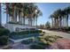 Welcoming Sun City Anthem entrance featuring neatly trimmed greenery and an array of stately palm trees at 2603 Savannah Springs Ave, Henderson, NV 89052