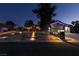 Charming home featuring a well-lit walkway, landscaped front yard, and a two-car garage at twilight at 3083 Paintedhills Ave, Las Vegas, NV 89120