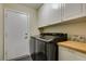 Functional laundry area with front-load washer/dryer, utility sink, and ample storage at 3083 Paintedhills Ave, Las Vegas, NV 89120