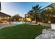 Backyard showcasing a manicured artificial lawn, backyard seating, and in the distance a refreshing pool at 3386 W Haleh Ave, Las Vegas, NV 89141