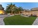 Spacious backyard with artificial turf, a stone retaining wall, mature trees, and ample seating for entertaining at 3386 W Haleh Ave, Las Vegas, NV 89141