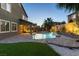 Evening shot of a backyard with a pool, spa, covered patio, and landscape lighting at 3386 W Haleh Ave, Las Vegas, NV 89141