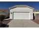 View of the garage of the home with a white garage door, brown rock landscaping, and a concrete driveway at 3761 Tohono Canyon St, Las Vegas, NV 89147