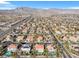 An aerial view displays a neighborhood with desert landscaping and terra cotta rooftops with a mountain backdrop at 4024 Mansion Hall Ct, Las Vegas, NV 89129