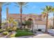 A two story beige home shows an arched entry, desert landscaping, an attached two car garage and palm trees at 4024 Mansion Hall Ct, Las Vegas, NV 89129