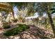 Serene backyard featuring verdant landscaping, decorative rock, mature trees, and a fenced perimeter at 4125 Gliding Gulls Ave, North Las Vegas, NV 89084