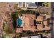 An aerial view showcases a large estate with a resort-style pool, surrounded by lush landscaping and desert terrain at 9801 Orient Express Ct, Las Vegas, NV 89145