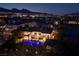 A luxury home displays an illuminated pool and architectural details against the twilight cityscape and mountain backdrop at 9801 Orient Express Ct, Las Vegas, NV 89145