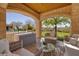 Outdoor patio with comfortable seating under an arched stone ceiling, overlooking the manicured lawn and backyard at 9801 Orient Express Ct, Las Vegas, NV 89145